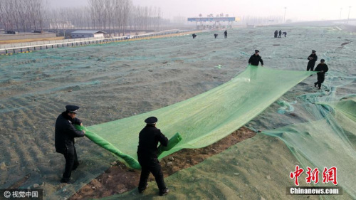 12月16日，北京大兴区城管队员正在苫盖建筑垃圾。视觉中国
