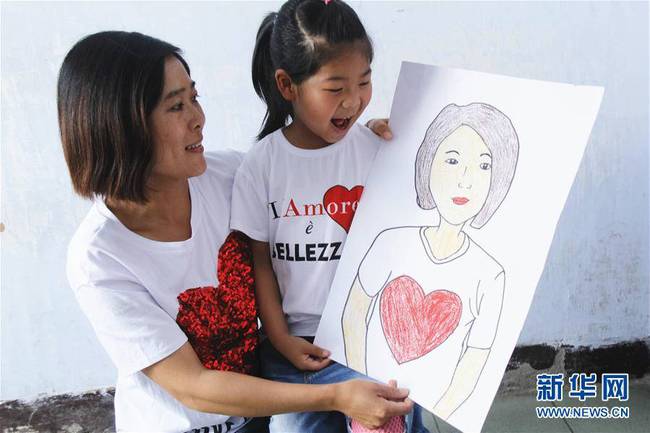 5月10日，在河北唐山市丰润区迎宾路幼儿园开展的“妈妈，我爱你”主题活动中，陈悦宁小朋友将自己的绘画作品送给妈妈作为节日礼物。 新华社发（朱大勇 摄）