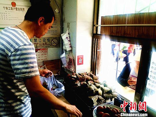 图为凌君道正在将粽子装袋进行售卖。　高康迪 摄