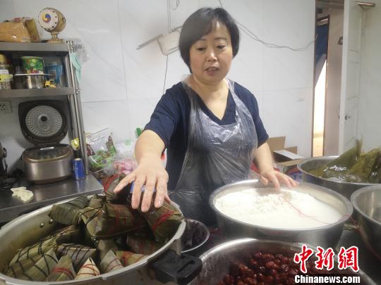 郑春玲将两张大粽叶窝成漏斗状，填上糯米，放上两粒红枣，再加一片小粽叶，用棉线缠绕绑好，一个红枣粽就成了，用时仅8秒。　高康迪 摄