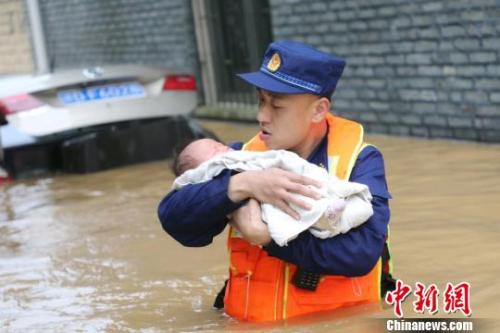 6月10日，江西省吉安县梅塘乡渡口村，消防员蹚着齐腰深的洪水，小心翼翼地将婴儿转移到安全地带。　郭清云 摄